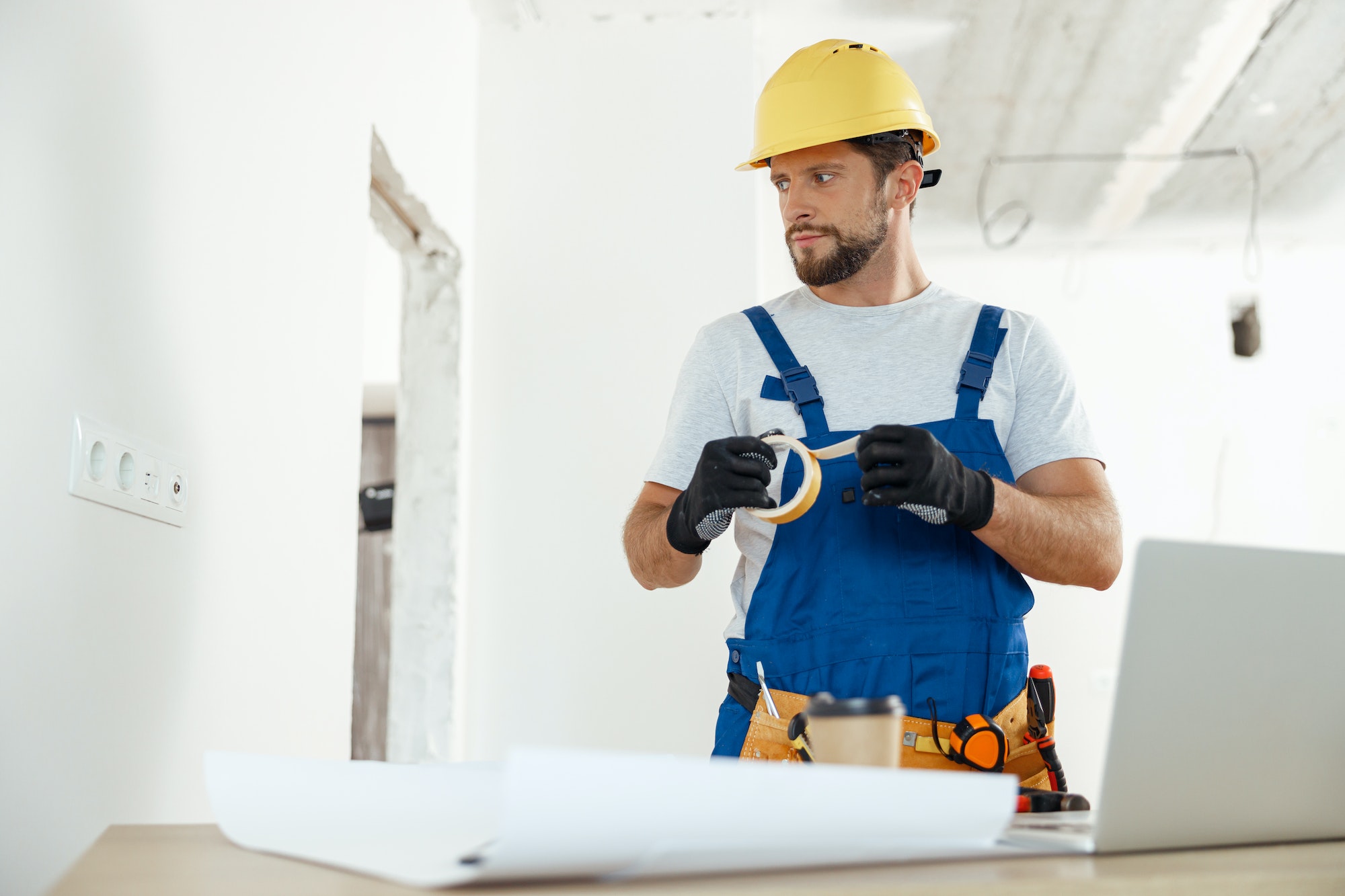 Busy handyman, electrician using insulating tape while installing new electrical socket outlet in